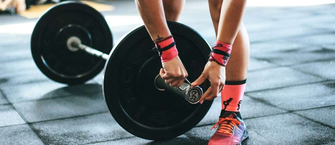 person locking gym plates on barbell
