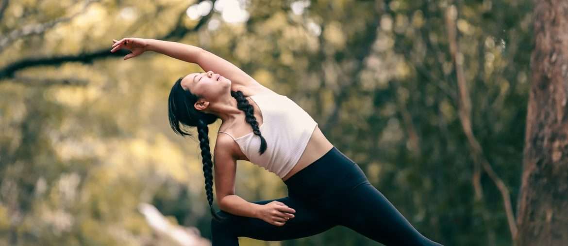 woman in white tank top and black leggings doing yoga during daytime