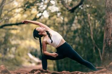 woman in white tank top and black leggings doing yoga during daytime