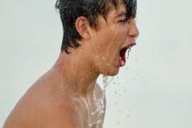 topless man with water droplets on his face