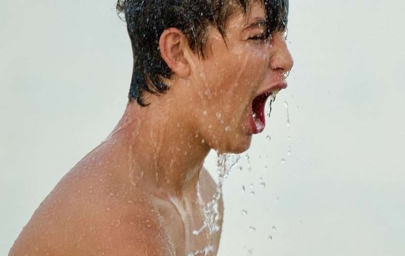 topless man with water droplets on his face