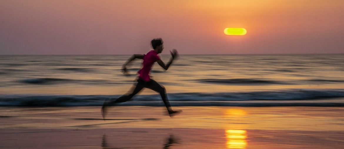 man running along seashore during golden hour